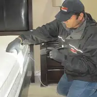 Bed bug inspection technician checking a mattress and bed frame for signs of infestation in Santa Ana, CA