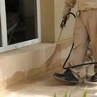 General pest control technician spraying exterior perimeter around a home in Santa Ana, CA