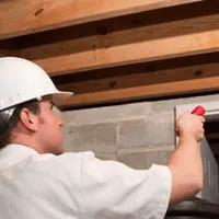 Termite inspection technician checking a basement wall and framing for termite activity in Santa Ana, CA
