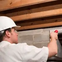 Termite inspection technician checking a basement wall and framing for termite activity in Santa Ana, CA